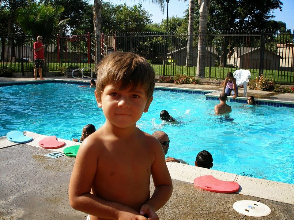 little boy standing in front of a pool
